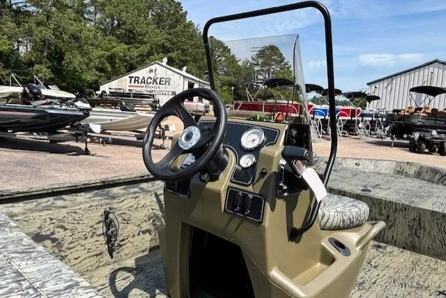 Slide: The Image of 2026 Tracker Grizzly 1860 CC boat with steering console, parked outdoors at a dealership. - 19