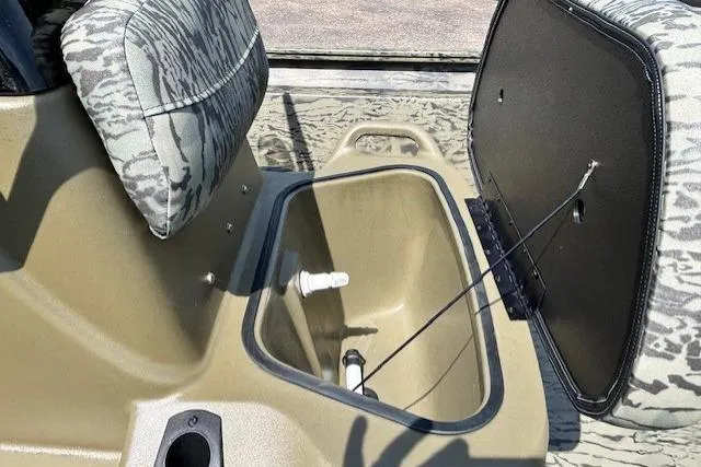 Slide: The Image of 2026 Tracker Grizzly 1860 CC boat interior with open storage compartment and camo seating. - 20
