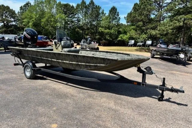 Slide: The Image of 2026 Tracker Grizzly 1860 CC boat on trailer, parked outdoors with trees in background. - 7