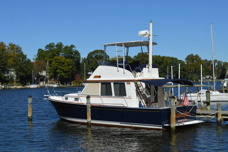 Slide: The Image of 2004 Sabre 36 yacht docked on a serene lake with trees in the background. - 3