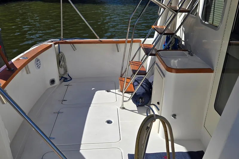 Slide: The Image of 2004 Sabre 36 boat deck with stairs, sink, and railing by the water. - 15