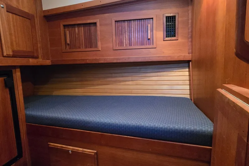 Slide: The Image of Wooden cabin interior with a blue cushioned berth in a 2004 Sabre 36 yacht. - 43