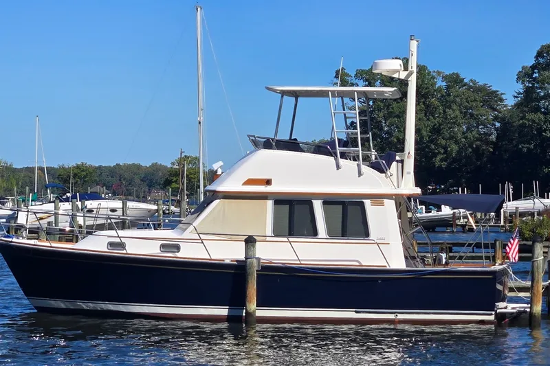 The Image of 2004 Sabre 36 yacht docked at a marina, surrounded by water and trees. - 0