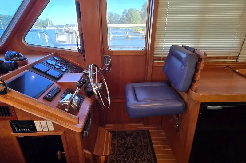 Slide: The Image of 2004 Sabre 36 yacht helm with wooden dashboard, steering wheel, and blue captain's chair. - 32