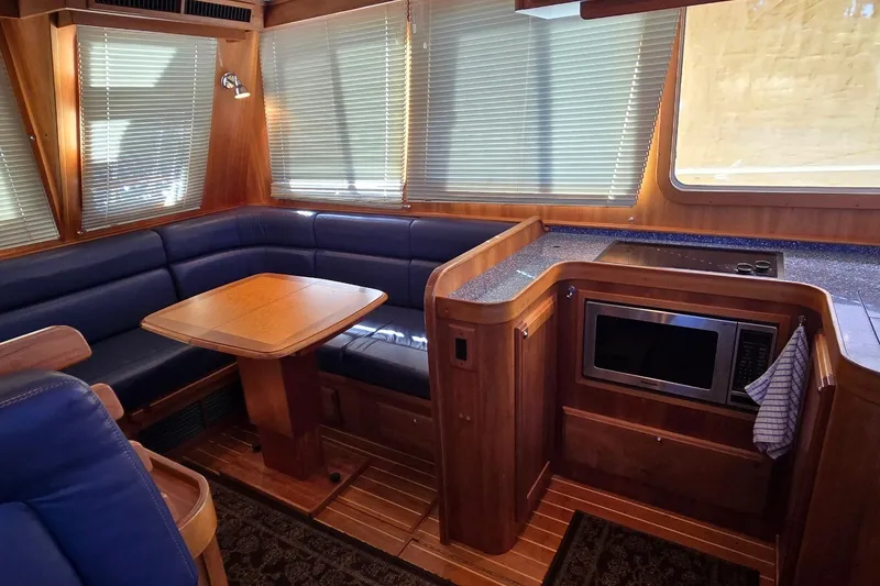 Slide: The Image of Interior of 2004 Sabre 36 yacht with wood finish, blue seating, and kitchenette. - 29