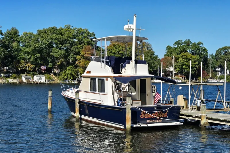 Slide: The Image of 2004 Sabre 36 boat docked on a serene lake with lush trees in the background. - 4