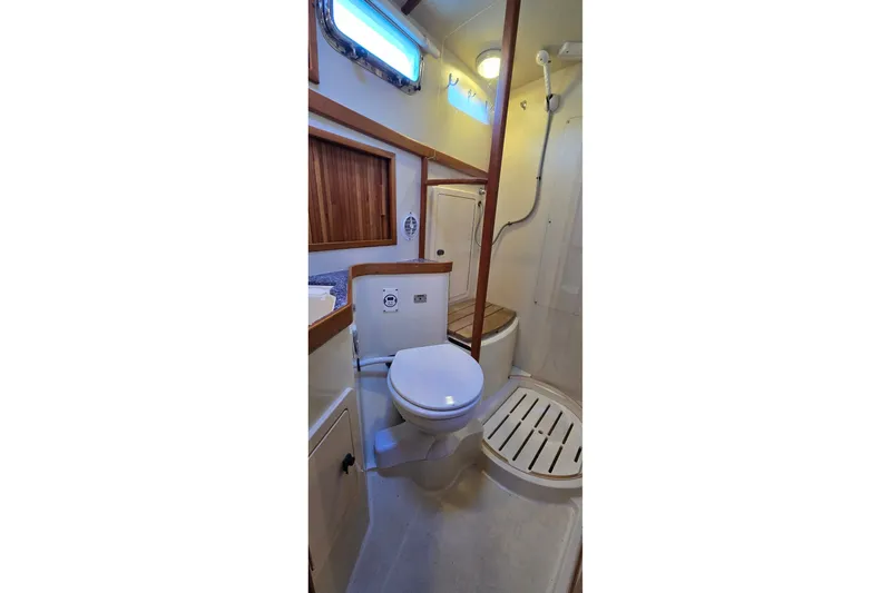 Slide: The Image of 2004 Sabre 36 yacht bathroom with toilet, shower, and wooden accents. - 48