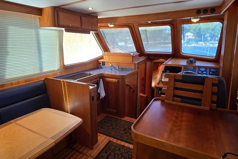 Slide: The Image of Interior of 2004 Sabre 36 yacht featuring wood finishes, dining area, and helm station. - 27
