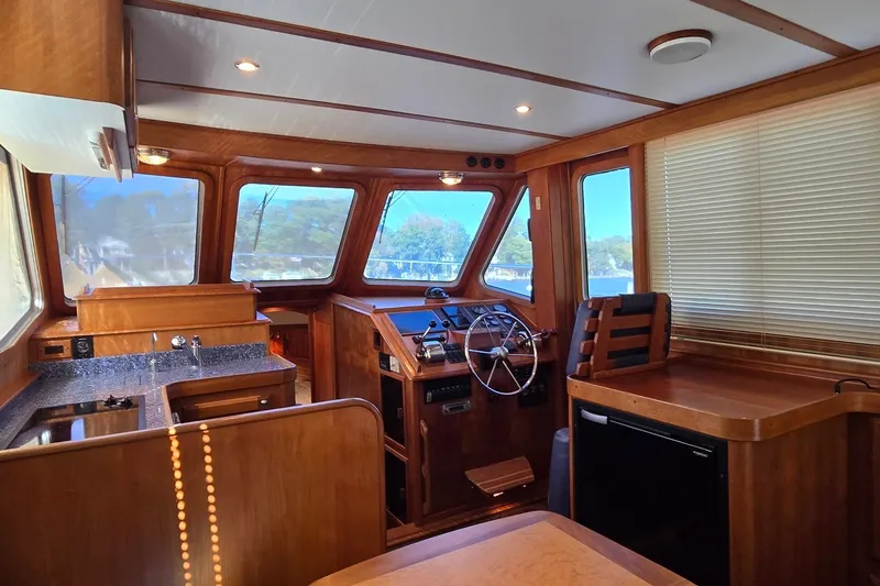Slide: The Image of Interior of a 2004 Sabre 36 boat featuring a wooden helm and kitchenette. - 30