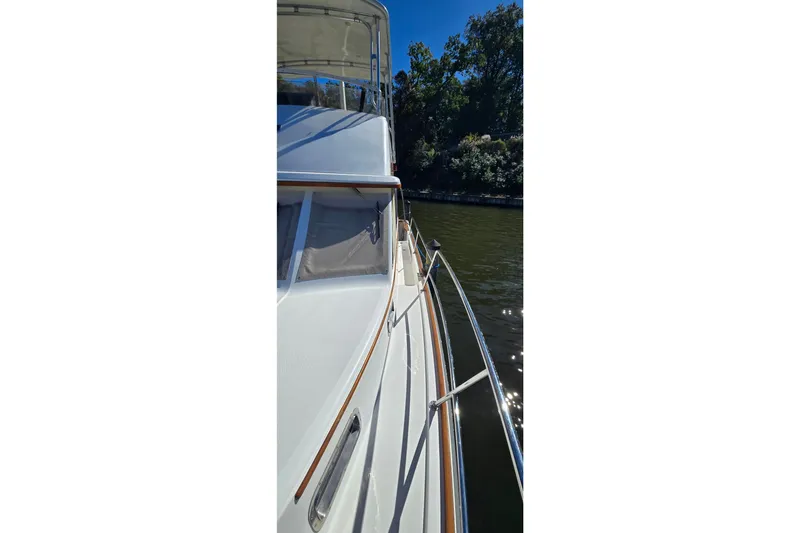 Slide: The Image of 2004 Sabre 36 yacht on calm water, surrounded by trees under clear blue sky. - 10