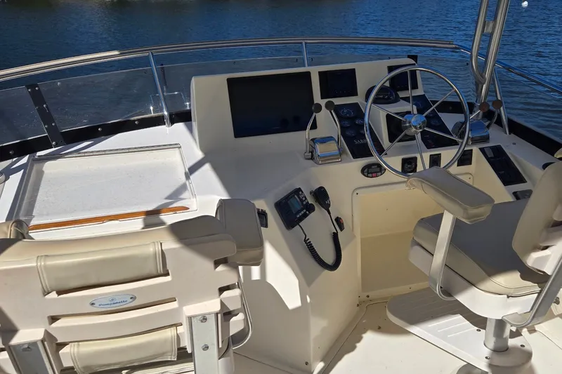 Slide: The Image of 2004 Sabre 36 boat helm with steering wheel, controls, and seating on a sunny day. - 17