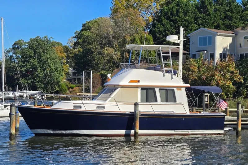 Slide: The Image of 2004 Sabre 36 yacht docked by waterfront homes, surrounded by lush greenery. - 1