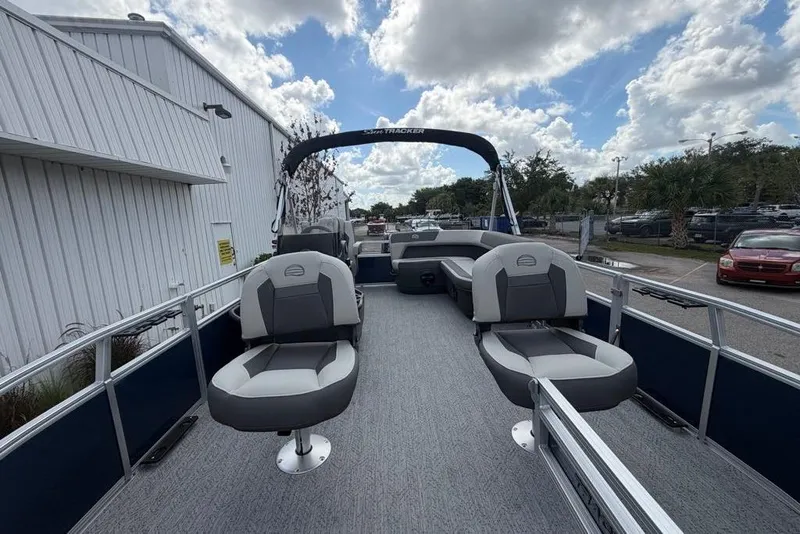 Slide: The Image of 2026 Sun Tracker Bass Buggy 16 XL Select pontoon boat with seating, docked outdoors. - 2