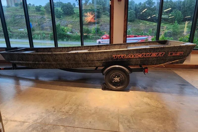 The Image of 2026 Tracker Grizzly 15 Jon boat displayed indoors with scenic window view. - 0