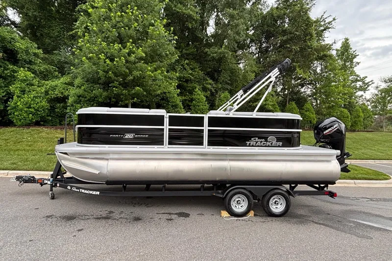 The Image of 2026 Sun Tracker Party Barge 20 DLX pontoon boat on trailer, parked on road. - 0