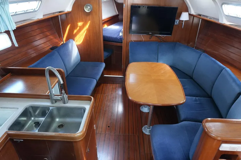 Slide: The Image of Interior of a 1999 Beneteau 381 yacht with wooden finish and blue seating. - 15