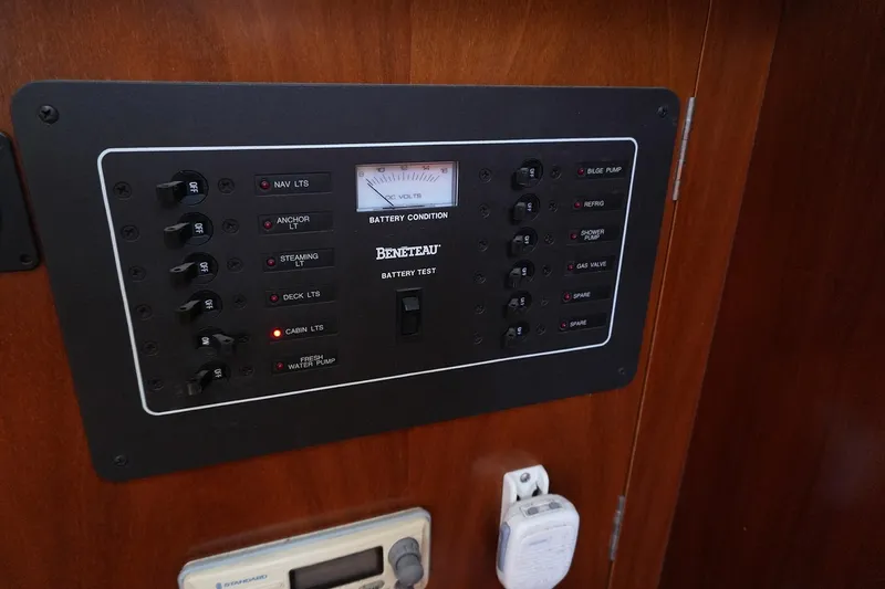 Slide: The Image of Electrical control panel on a 1999 Beneteau 381 sailboat, featuring various switches and a battery condition meter. - 22