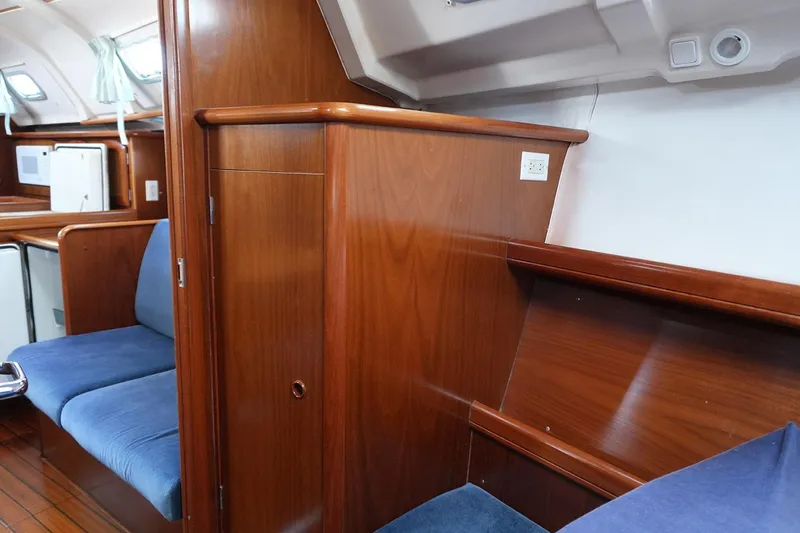 Slide: The Image of Interior of a 1999 Beneteau 381 sailboat with wooden cabinetry and blue seating. - 26
