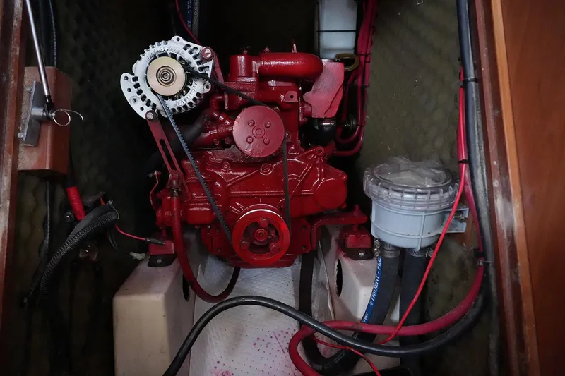 Slide: The Image of Engine compartment of a 1999 Beneteau 381 sailboat, featuring a red engine and wiring. - 33