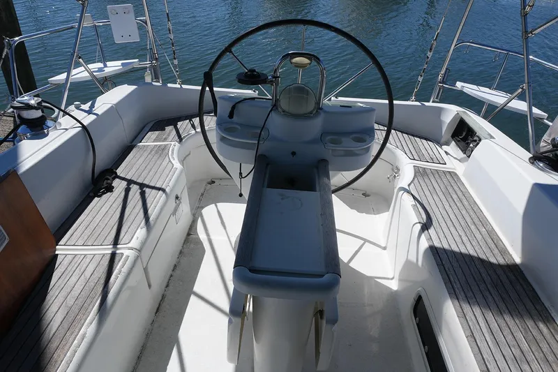 Slide: The Image of Cockpit of 1999 Beneteau 381 sailboat with steering wheel and seating, docked on water. - 8