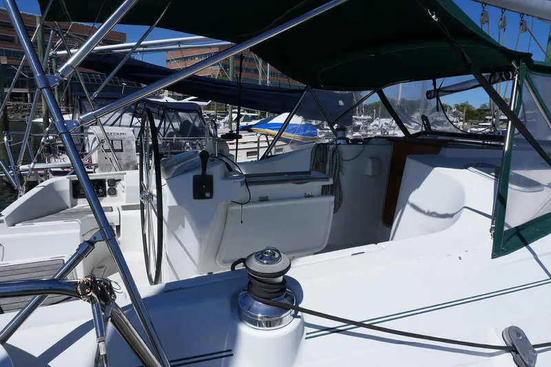 Slide: The Image of 1999 Beneteau 381 sailboat cockpit with steering wheel and marina background. - 9