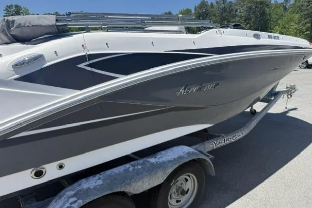 Slide: The Image of 2021 Hurricane SunDeck Sport 205 OB boat on trailer, sleek design, parked outdoors. - 2
