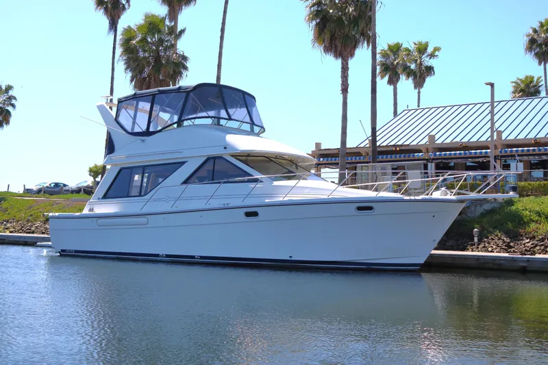 The Image of 1999 Bayliner 3988 Command Bridge Motoryacht docked near palm trees and a building. - 1