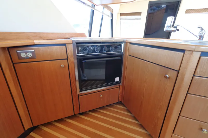 Slide: The Image of Kitchen area of 1999 Bayliner 3988 Command Bridge Motoryacht with wood cabinetry and oven. - 30