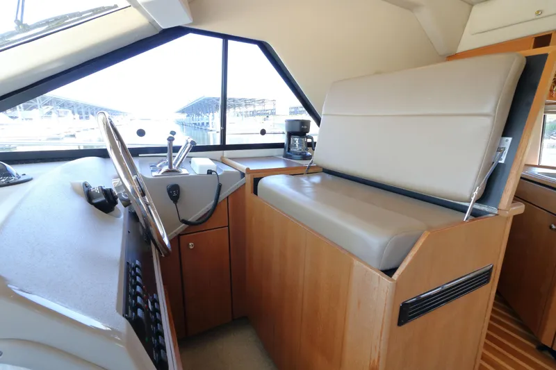 Slide: The Image of 1999 Bayliner 3988 Command Bridge Motoryacht helm with steering wheel and beige seating. - 33