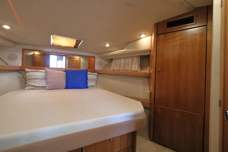 Slide: The Image of 1999 Bayliner 3988 Command Bridge Motoryacht cabin with bed, pillows, and wooden cabinetry. - 39