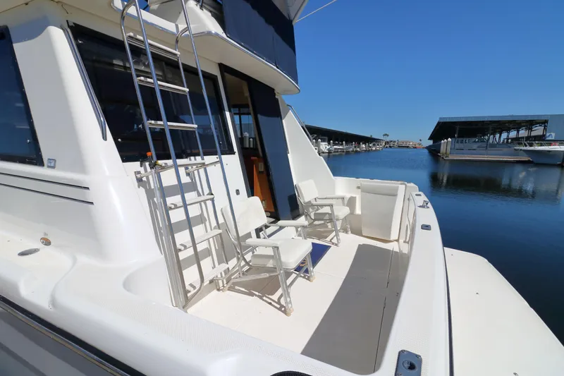 Slide: The Image of 1999 Bayliner 3988 Command Bridge Motoryacht docked, featuring spacious deck with chairs and ladder. - 6