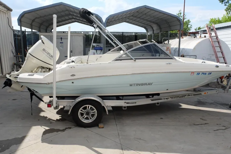 The Image of 2020 Stingray 191 DC boat on trailer with Suzuki outboard motor in storage area. - 1