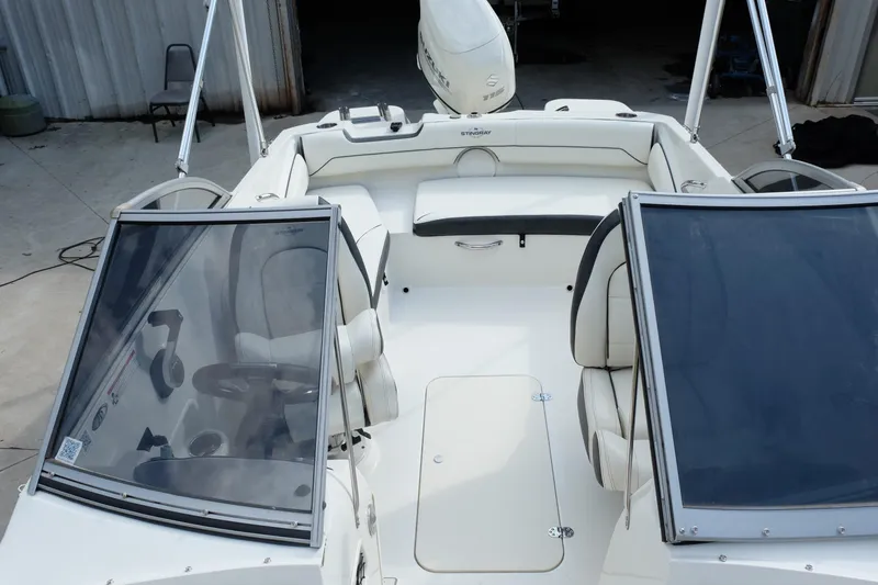 Slide: The Image of 2020 Stingray 191 DC boat interior with seating and windshield, parked in a garage. - 13