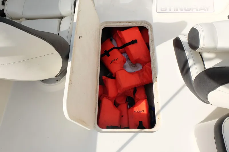Slide: The Image of Storage compartment with orange life jackets on a 2020 Stingray 191 DC boat. - 19