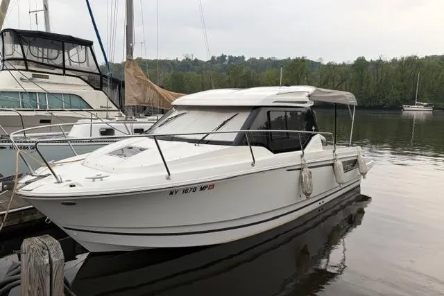 The Image of 2019 Jeanneau NC 795 boat docked on a calm river with lush greenery. - 0