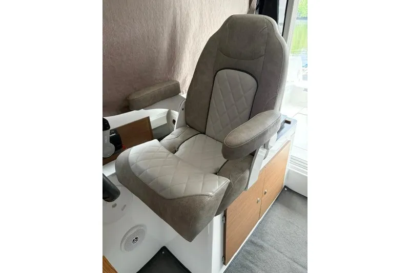 Slide: The Image of Captain's seat in 2019 Jeanneau NC 795 boat, featuring cushioned armrests and quilted upholstery. - 5
