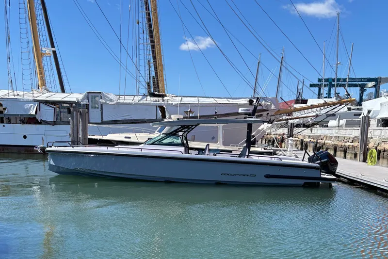 The Image of 2025 Axopar 37 Sun-Top boat docked in a marina, surrounded by sailboats. - 0