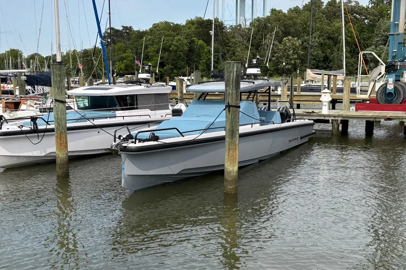 Slide: The Image of 2025 Axopar 37 Sun-Top boat docked at a marina, surrounded by other vessels. - 10