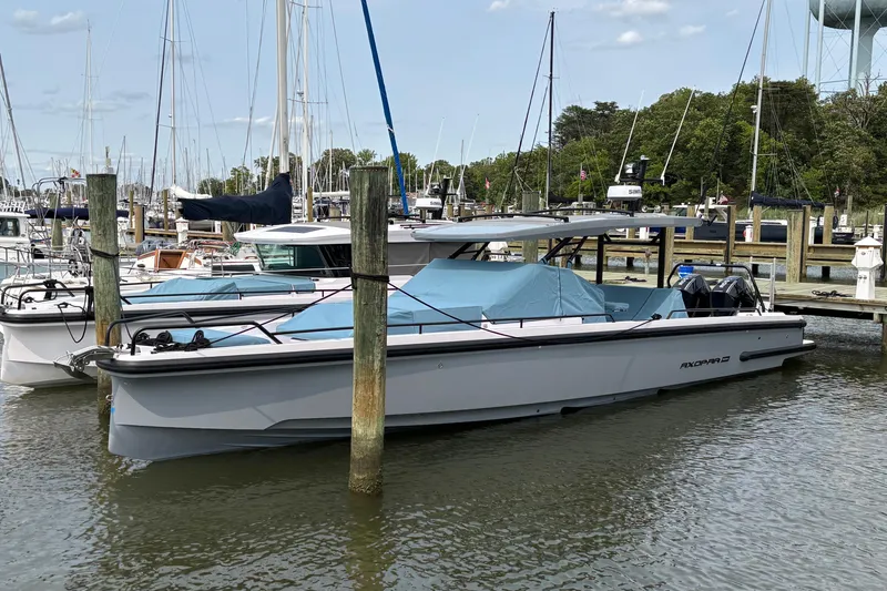 Slide: The Image of 2025 Axopar 37 Sun-Top boat docked at a marina, surrounded by other vessels. - 11