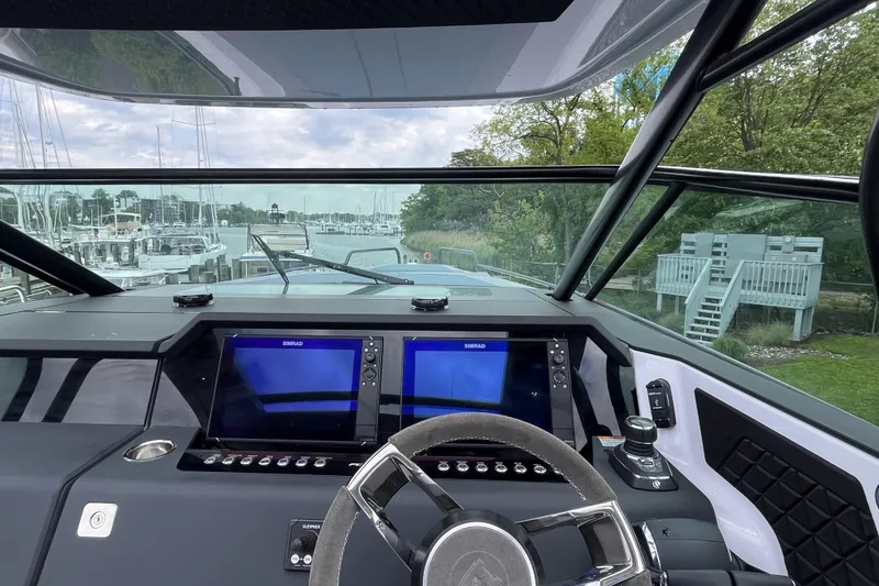 Slide: The Image of Cockpit view of 2025 Axopar 37 Sun-Top with dual navigation screens at marina. - 15