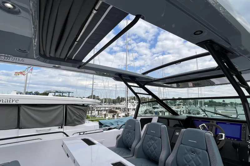 Slide: The Image of 2025 Axopar 37 Sun-Top boat interior with open roof and modern seating at marina. - 22