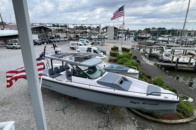 Slide: The Image of 2025 Axopar 37 Sun-Top boat displayed at a marina with American flags. - 23