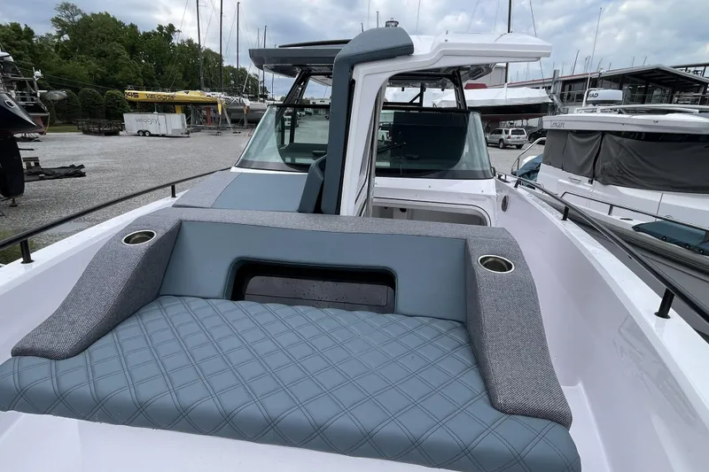 Slide: The Image of 2025 Axopar 37 Sun-Top boat with stylish seating and modern design in a marina setting. - 39