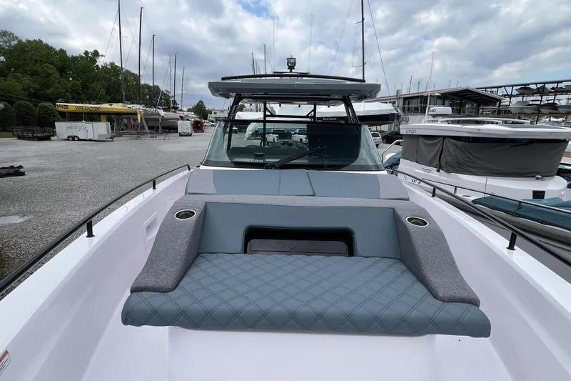 Slide: The Image of 2025 Axopar 37 Sun-Top boat with sleek design and comfortable seating at a marina. - 43