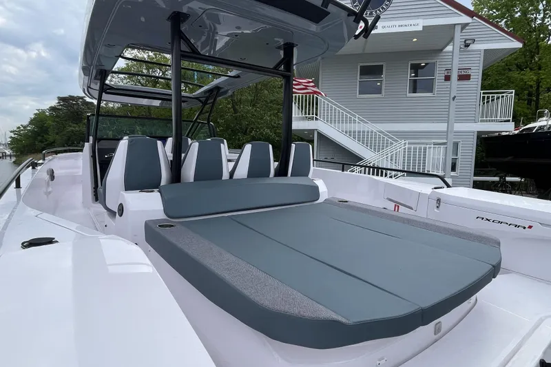 Slide: The Image of 2025 Axopar 37 Sun-Top boat with sleek seating and modern design near a marina. - 44