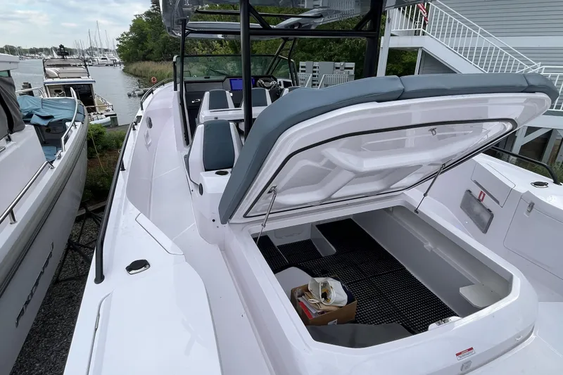 Slide: The Image of 2025 Axopar 37 Sun-Top boat with open storage compartment, docked near marina. - 47