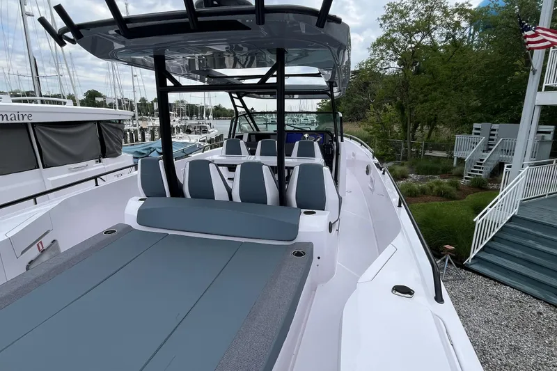 Slide: The Image of 2025 Axopar 37 Sun-Top boat with sleek seating and modern design at a marina. - 48