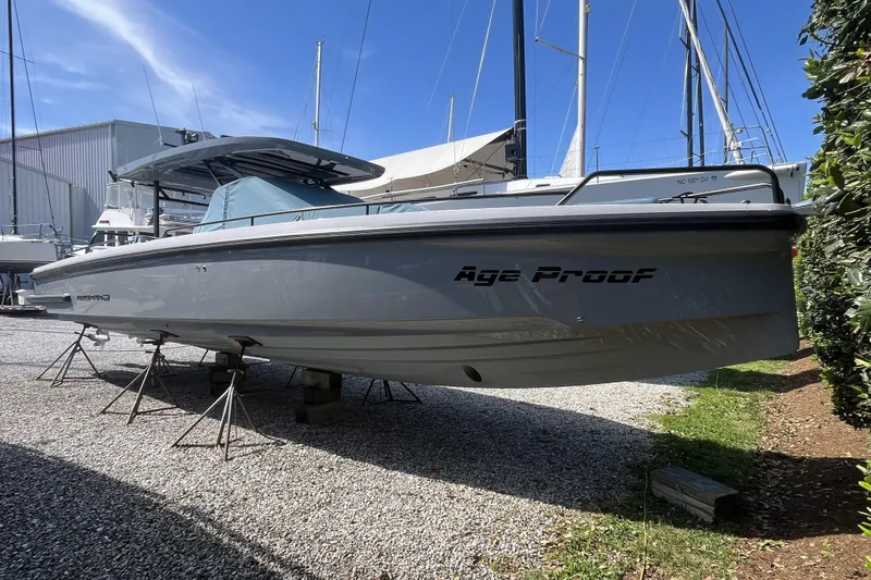 Slide: The Image of 2025 Axopar 37 Sun-Top boat on stands, labeled "Age Proof," in a marina setting. - 5