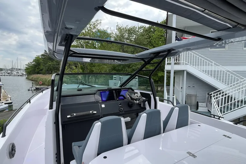 Slide: The Image of 2025 Axopar 37 Sun-Top boat interior with modern dashboard and seating, docked near marina. - 54