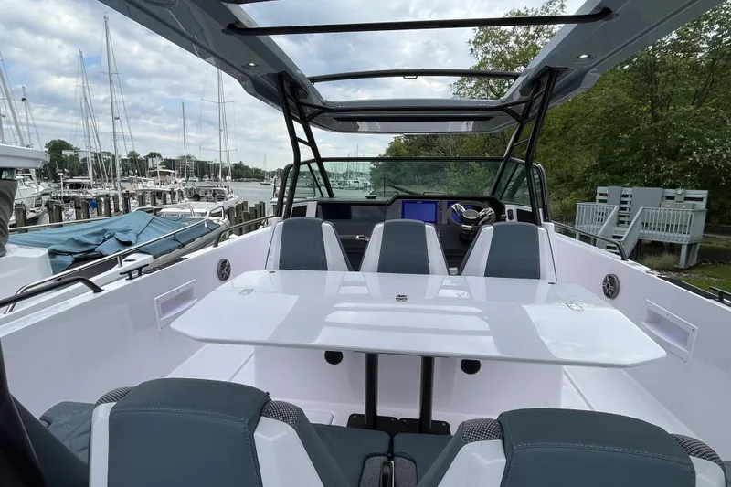 Slide: The Image of 2025 Axopar 37 Sun-Top boat interior with sleek seating and modern design at a marina. - 57
